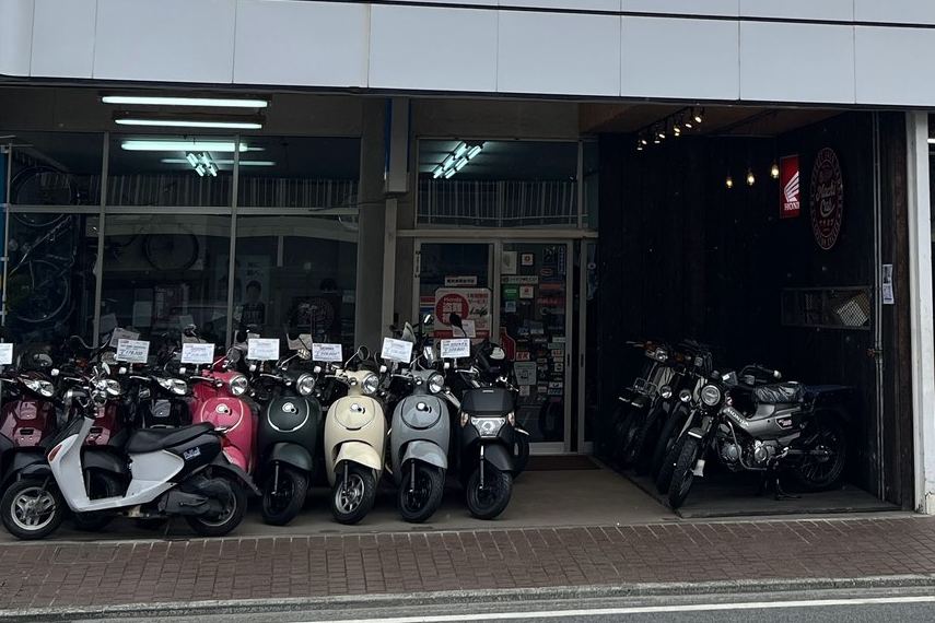 店先に並ぶスクーターと、ガラス越しの自転車